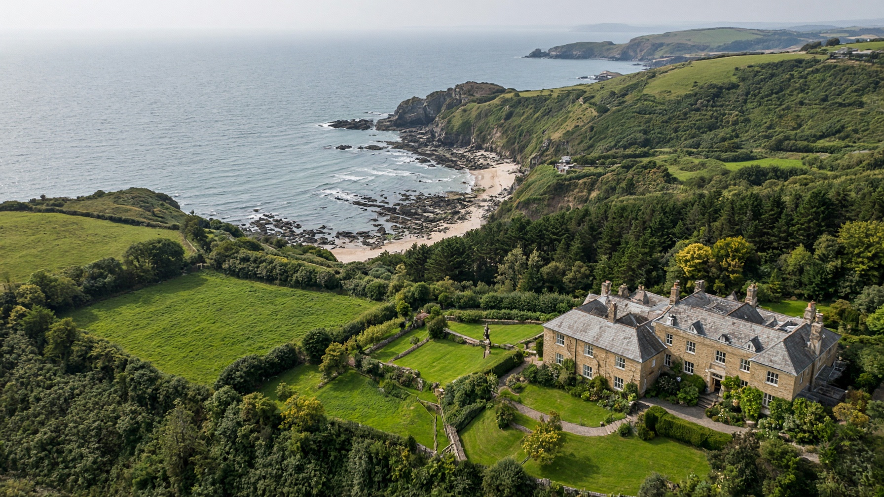 Aerial view of Pearl Bay, a stone house above a crescent bay